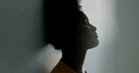 Silhouette young black woman leaning on wall. Pensive African girl