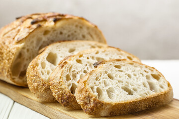 Sliced freshly baked wheat bread on wooden board, selective focus. Bakery concept.