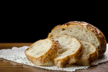 Close up of slices of freshly wheat bread on napkin on table on black background, selective focus. Bakery concept.