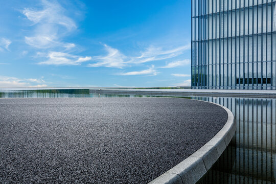Asphalt road platform and glass wall building with sky cloud background
