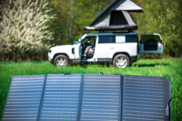 4x4 Offroad vehicle camping with roof tent in a meadwow with solar panel for energy generation in...