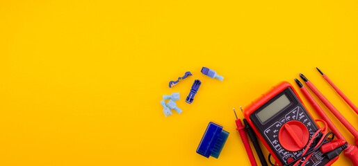 Arrangement of tools for repairing automotive electrical wiring on a yellow background.