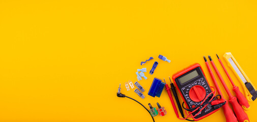 Arrangement of tools for repairing automotive electrical wiring on a yellow background.