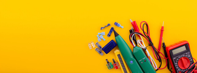 Arrangement of tools for repairing automotive electrical wiring on a yellow background.