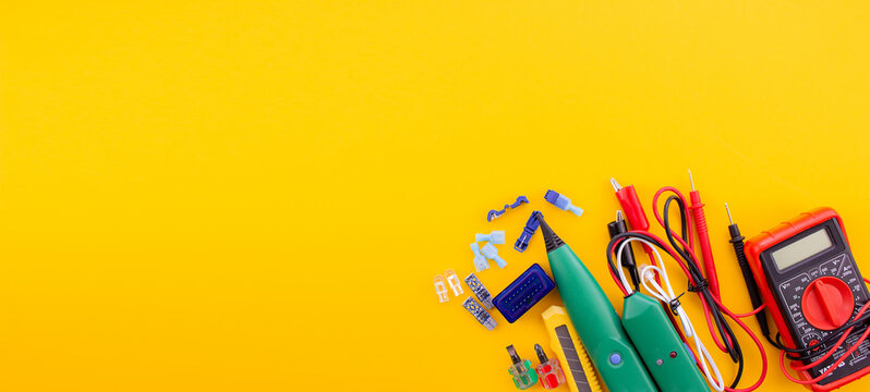 Arrangement of tools for repairing automotive electrical wiring on a yellow background.