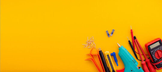 Arrangement of tools for repairing automotive electrical wiring on a yellow background.