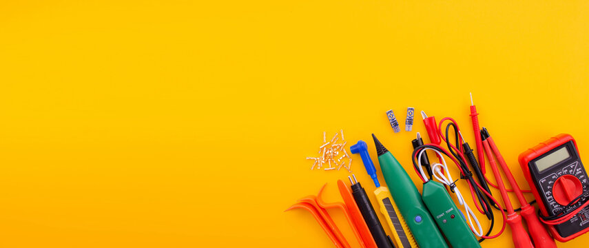Arrangement of tools for repairing automotive electrical wiring on a yellow background.