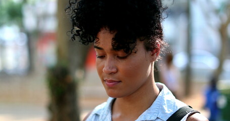 Contemplative hispanic black woman standing outside thinking