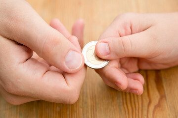 Obraz na płótnie Canvas Adult giving coin to a child as saving money concept. Children's financial education, financial literacy. Payment for duties performed.