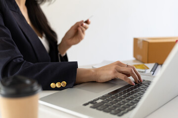 Businesswoman holding a credit card and using a laptop. Concept of online money transactions through laptop and online shopping.