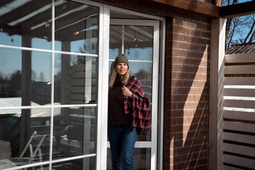 beautiful smiling young woman with plaid on terrace of cozy modern country house