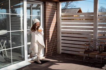 Happy woman drinking lemonade in backyard of modern country house