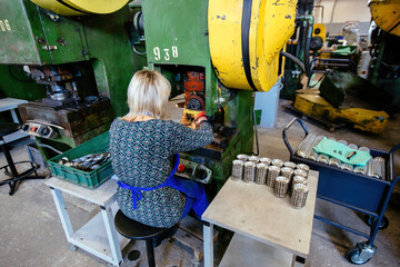 Worker operates metal press stamping machine. Production of press forms for cookies