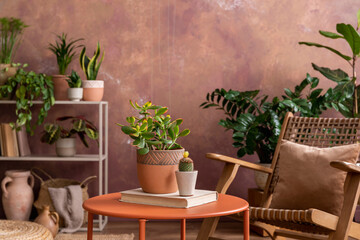 Stylish composition of creative spacious living room interior with plants, rattan armchair, coffee table and stylish accessories. Botanical space of a cozy room. Brown walls . Template.