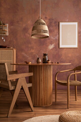 Stylish boho vintage dining room interior with poster mock up. Round table with rattan chair, vase with dried flowers. Brown wall and rattan lamp. Mock up poster. Template.