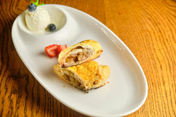 A piece of apple strudel with vanilla ice cream and strawberries