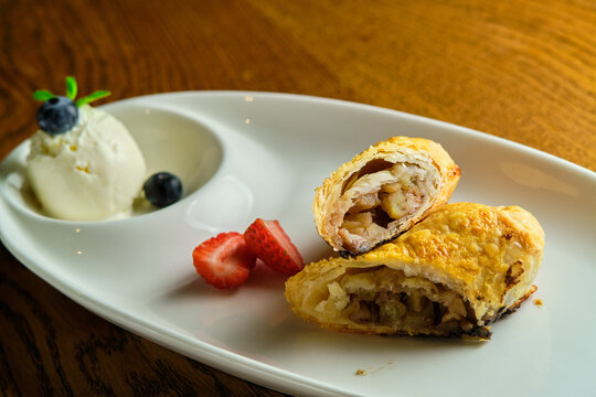 A piece of apple strudel with vanilla ice cream and strawberries