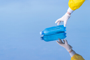 Close-up of a blue cap on a bottle. A hand in a white glove collects debris from the surface of the water. Pond cleaning. Copy space.