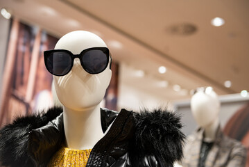 Fashion mannequins at storefront window in shopping mall. Midseason sale at style clothes retailer. Discount designer apparel displayed in shop or boutique.