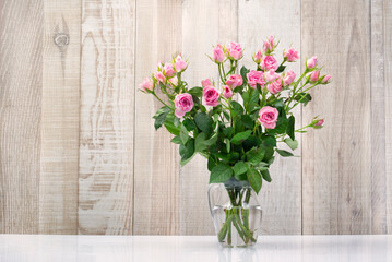 bouquet of bouquet pink roses in water in a glass vase wooden background