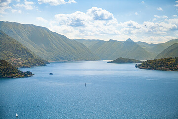 Panoramic aerial view of Lake Como from Varenna towards Bellagio with clear sky in summer and boats on the water.