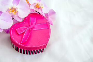 gift box in the form of heart and an orchid on white fabric