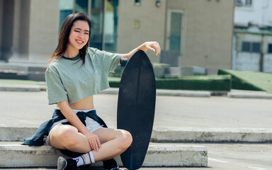 Portrait beautiful sportive Asian female skater wearing hipster shirt with shorts, smiling with...