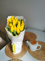 Beautiful yellow tulips on a white table with a teapot.