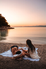 Couple on the beach watching the sunset on isl. Brac, Croatia.