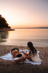Obraz premium Couple on the beach watching the sunset on isl. Brac, Croatia.