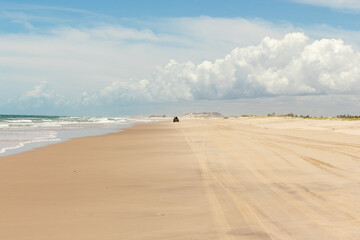 deserted beach with buggy, dunes, vegetation, blue sky and clouds