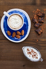 Blue cup of cappuccino almonds chocolate and milk in a glass milk jug