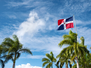 Flying and waving flag of Dominican Republic on wind on sky background - obrazy, fototapety, plakaty