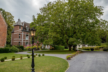 Fototapeta premium Yard with big tree. Travel perspective, cloudy summer day. Monastery of Saint-Charbel at the Abbey of Bois Seigneur Isaac.