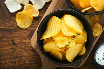 Potato corrugatedchips. Fast food. Crispy potato chips ceramic black bowl with sour cream sauce and...