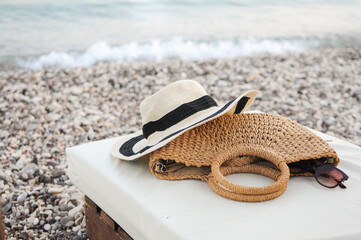 Beach flat lay accessories: straw hat, summer bag, and sunglasses on sunbed