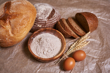 Fresh fried bread with wheat flour on wooden table closeup