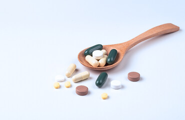  Pills and tablets in wooden spoon on white background. health care and medical concept.