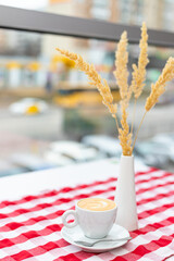 A cup of cappuccino stands on the table in a cafe in a bright interior