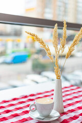 A cup of cappuccino stands on the table in a cafe in a bright interior