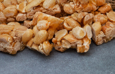 Peanut brittle, an old school sweet favorite, cut into small bars on rustic type surface with copy space