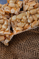 Peanut brittle, an old school sweet favorite, cut into small bars on rustic type surface with copy space