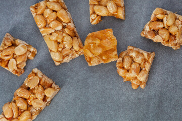 Peanut brittle, an old school sweet favorite, cut into small bars on rustic type surface with copy space