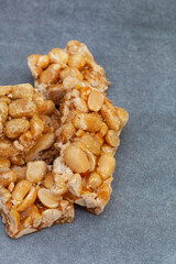 Peanut brittle, an old school sweet favorite, cut into small bars on rustic type surface with copy space