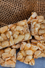 Peanut brittle, an old school sweet favorite, cut into small bars on rustic type surface with copy space