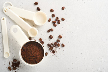 Coffee background. Measuring spoons with ground coffee and beans on old tile cracked table background. Ingredients for making coffee. Top view with space for your text