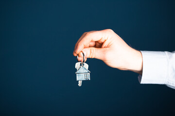 A man in a business suit holds out the keys in his hand.