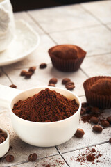 Coffee background. Measuring spoons with ground coffee, beans, cup and sweet chocolate truffles on old tile cracked table background. Food background. Top view with space for your text