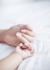 Asian parent hands holding newborn baby fingers, Close up mother’s hand holding their new born...