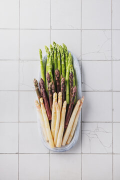 Green, purple and white asparagus on kitchen tiles 